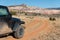 Four-wheel drive vehicle on a curving dirt road driving towards a colorful high desert peak in Ghost Ranch, New Mexico