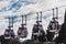 The four white cabins of the cable cars with transparent windows and people under brown roofs on the blue sky with white clouds