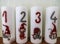 Four white candles with painted numbers and gnomes