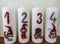 Four white candles with painted numbers and gnomes