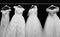 Four white wedding dresses on a black background.