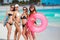 Four women in bikinis with lifeline near the ocean.