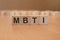 four wooden blocks with the letters MBTI - on the bright surface of a blue table. the inscription on the cubes is