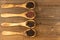 Four wooden cooking spoons made of olive wood filled with different peppercorns