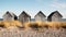 Four wooden huts on a sandy beach on a sunny day