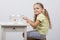 Four-year girl sitting in front of an aquarium with goldfish and knocks his finger on it