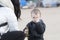 Four Year Old Boy Holding a Dinosaur on a Beach in Winter with Sand in Eye. Mom looking on