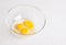 Four yellow yolks with egg protein in a deep plate  before cooking on a white isolated background