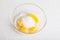 Four yellow yolks with egg protein and sugar in a deep plate  before cooking on a white isolated background