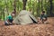 Four young cheerful best friends are setting up a tent in forest