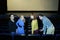 Four young friends sit down on seats in cinema theater hall