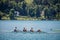 Four young male adults, rowers, on a coxed four, a rowing boat, training for rowing for an aviron competition on the Bled lake