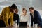 Four young multiracial adults in businesswear having meeting around digital tablet in office