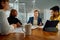 Four young multiracial adults in businesswear smiling in conference room with digital tablet in office