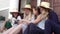 Four young stylish women in straw hats are sitting at the street