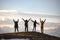 Four young tourists with backpacks in winner poses at mountain top