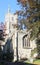 Fowey parish church, St Fimbarrus, under clear blue sky and framed by trees. Fowey is in Cornwall, England.