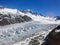 Fox glacier over black volcano rock and clear blue sky