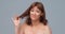 Foxy woman looks at camera holding split ends of hair. Pretty Caucasian naked woman portrait. Hair care concept. Cut out