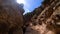 FPV drone backwards shot along yellow canyon, with people walking by blue water