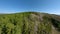 FPV sports drone flight mountain ridge stone structure spruce forest trees valley at clear blue sky