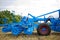 Fragment of agricultural machinery in blue standing in the field