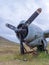 A fragment of airplane wing with three-bladed aircraft propeller against cloudy sky