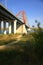 A fragment of an automobile bridge with supports and a red cable-stayed arch taken from a lower angle