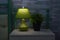 Fragment of a bedroom with a bedside table and a bed. A table lamp and a houseplant are on the nightstand