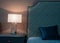Fragment of a bedroom with a bedside table and a bed. A table lamp is on the nightstand