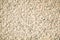 Fragment of a beige granite facing slab. Untreated scabrous stone surface of natural beige granite.