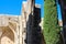 Fragment of Bellapais Abbey, White Abbey, Abbey of the Beautiful world. Side view of Arches and cypress trees against a blue sky