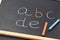 Fragment of Black Chalkboard with Hand Written Latin Alphabet Multicolored Chalks. Back to School Education Reading Literacy
