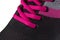 A fragment of a black sneaker with pink laces close-up.