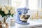 Fragment of classic white kitchen. Blue planetary mixer with stainless steel bowl, cup with ingredients, bouquet of