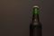 Fragment of a closed green bottle with dark beer on a black background