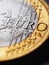 Fragment of a coin of 1 one euro. In focus inscription with the name of the Eurozone currency. Close-up. Dramatic dark vertical