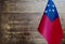 Fragment of the flag of the Independent state of Samoa in the foreground blurred wooden background copy space