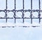 Fragment of a forged fence with round details covered with snow