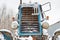 Fragment of the front of an old tractor covered with snow on a background cloudy winter sky