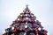 A fragment of a huge Christmas tree with many ornaments, gift boxes and luminous lamps. Photo of a decorated Christmas tree close-