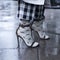 Fragment of legs in checkered trousers. Open high-heeled sandals and transparent floral socks