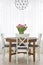 Fragment of light dining room with round wood table and bouquet or pink and red tulips