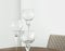 Fragment of living room interior with table setting various size wine glasses on dark wood table upholstered chair white wall