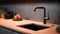 Fragment of modern minimalist kitchen. Stone peach countertop with built-in sink and black faucet. Dark gray backsplash