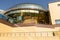 Fragment of new building of warm colors with spheric upper side tiled with golden glass panels against clear sky