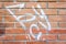 Fragment of an old damaged red brick wall with graffiti marks. Texture and background.