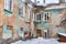 Fragment of an old dilapidated building with snowdrifts in the backyard