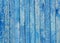 Fragment of an old fence. Cracked azure paint texture. Light blue wooden planks background.