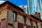 Fragment of an old ruined brick building against the background of a fragment of the glass facade of an office building